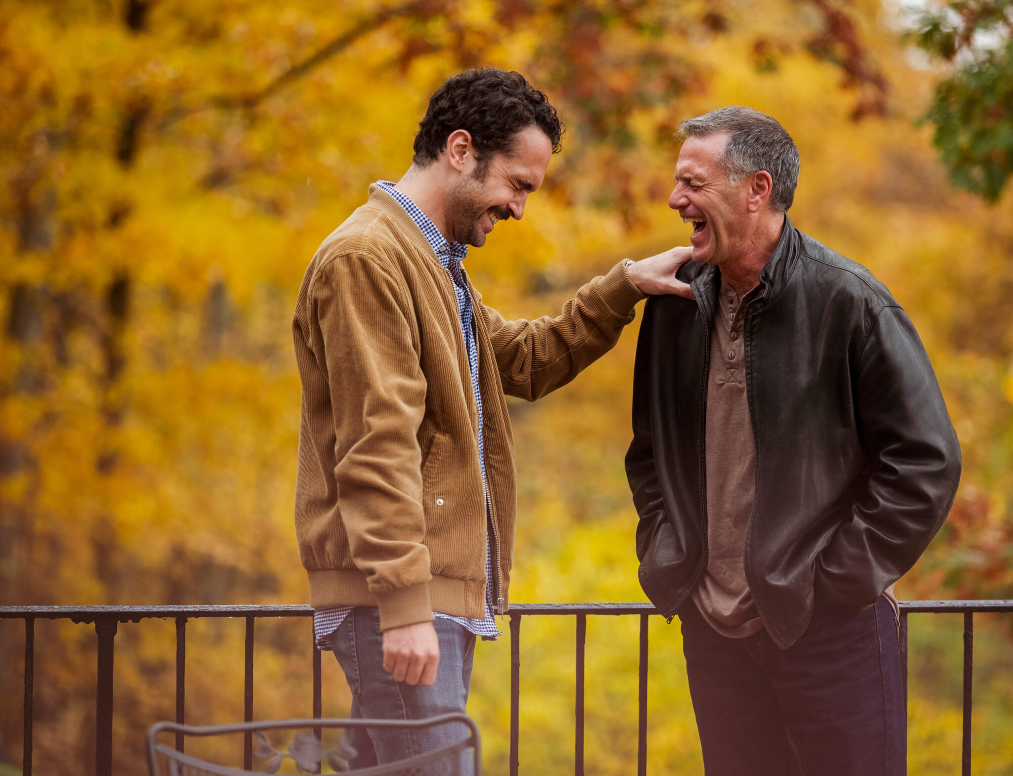 Mature Man Laughing While Standing With Son In Balcony During Autumn Mature Man Laughing While Standing With Son In Balcony During Autumn